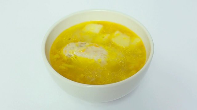 Portion of chicken soup in white bowl rotating slowly on white background. Healthy food concept.
