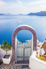 Obraz na płótnie Canvas Traditional fence gate in Oia on Santorini island, Greece. Aegean sea and Caldera in the background. Blue sky, travel, vacation time.