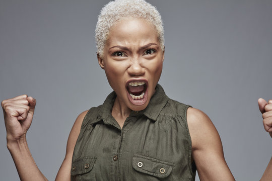 Portrait of screaming woman in front of grey background