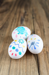 Obraz na płótnie Canvas Easter background with copy space, selective focus. Homemade baby's hand painted easter eggs isolated close-up over retro wooden rustic background