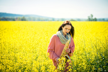 Woman playing saxophone in rapeseed field