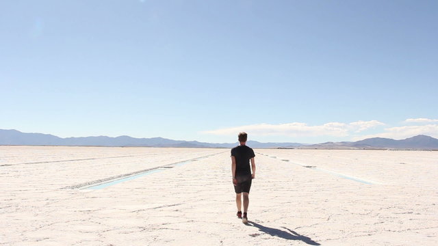A man walks away from camera across Salt Flats in Northern Argentina. 