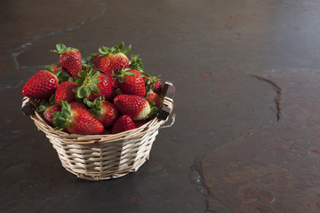 Fresh strawberries basket on dark stone table