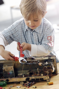 Little boy disassembling an old radio