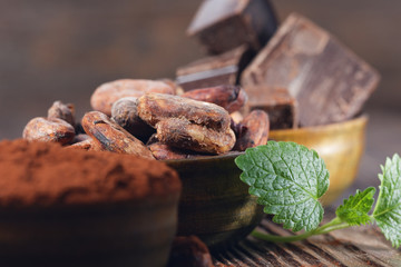 Dark chocolate pieces, cocoa powder and cocoa beans on a wooden table
