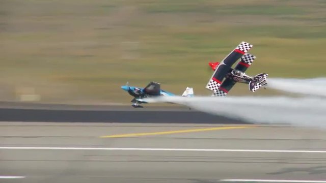 Two biplanes perform a dangerous stunt at an airshow.