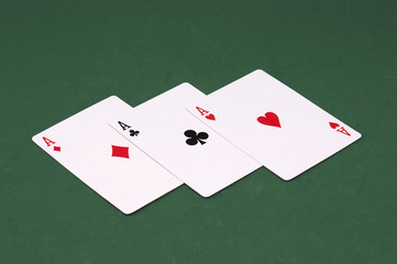 Three poker ace cards on green background.