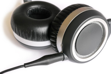 Black headphones on white background.Close-up view of modern earphones with cable.