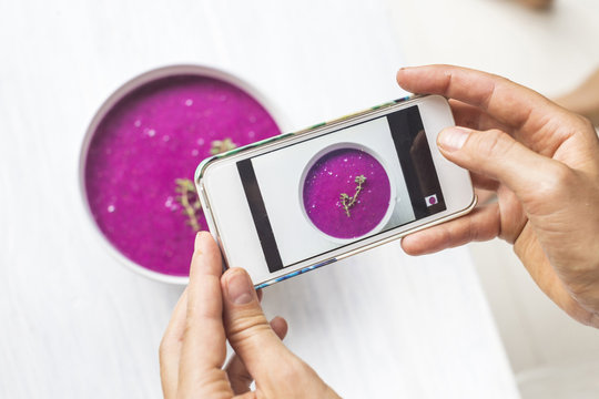 Woman taking a photo of dragon fruit smoothie with her smartphone, close-up