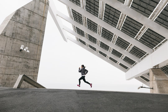 Spain, Barcelona, jogging woman under solar plant