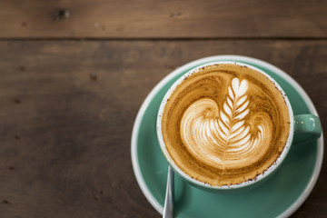 hot cappuccino with latte art on wood background