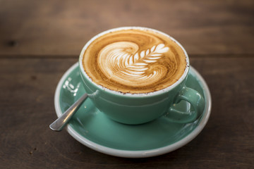 hot cappuccino with latte art on wood background