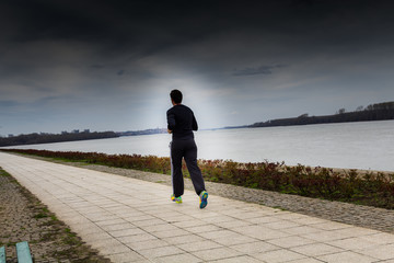 Young man run along the river, Danube