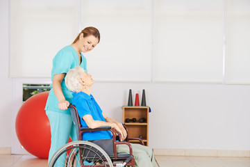Krankenpflegerin schiebt alte Frau im Rollstuhl