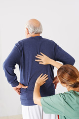 Senior mit Rückenschmerzen bei Physiotherapie