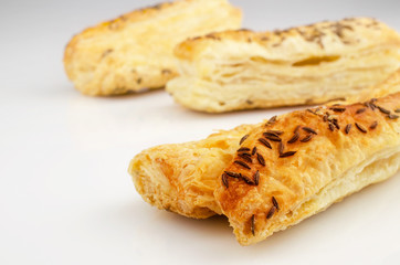 Confectionery theme. Puff pastry, topped with caraway seeds, on white surface. 