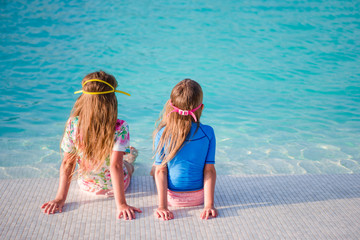 Fototapeta na wymiar Adorable little girls in outdoor swimming pool