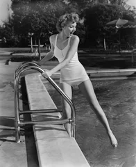 Fotobehang Vrouw duikt tenen in buitenzwembad © everettovrk