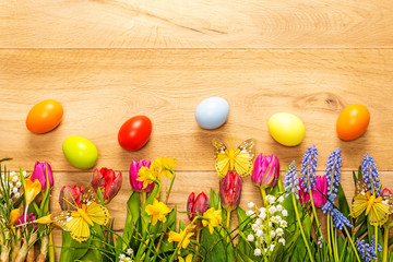 Wooden background with spring flowers, butterflies and easter eg