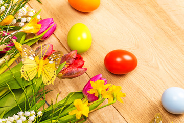 Wooden background with spring flowers, easter eggs and butterfli