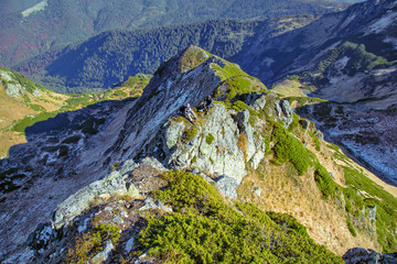 Obraz premium two hikers sitting on high mountain rock, aerial view