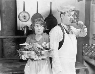 Couple standing together in a kitchen with a cooked turkey 