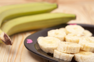 green banana with slices on wooden background