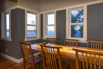 Dining area with wood table and chairs, painted walls and view windows with white window trim in...