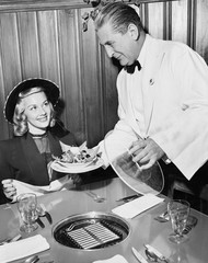 Waiter serving food to a woman at a restaurant 