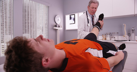 Mid-aged physical therapist examining college athlete sports inj
