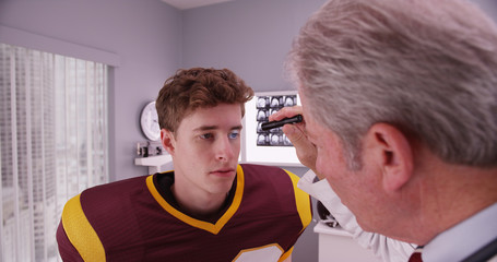 Mid-aged doctor examining football player after concussion