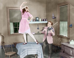 Man playing violin for woman dancing on table  