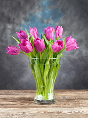 Beautiful tulips in glass vase on background