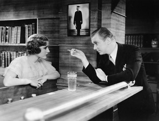 Man and woman standing together at a bar counter and talking 