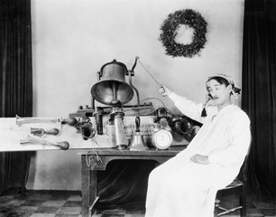 Man in a nightgown and sleeping cap ringing a big bell 