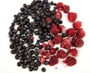 Blueberry and raspberries on white background. different kinds of berries. Ripe berries . Use it for a health concept. bilberry and raspberry fruits at white ceramic plate