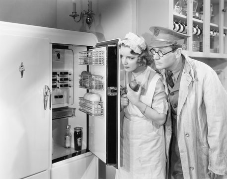 Man And Woman Standing In Front Of A Refrigerator 