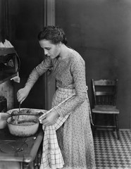 Profile of a young woman cooking food in the kitchen 