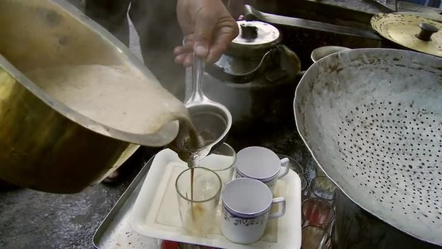 Man pouring chai tea into cups 