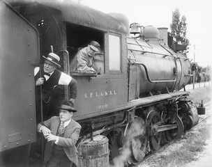 Three men waiting at a steam locomotive 