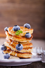 Pancake folded stack of with liquid honey and fresh blueberries on wooden background.selective focus.