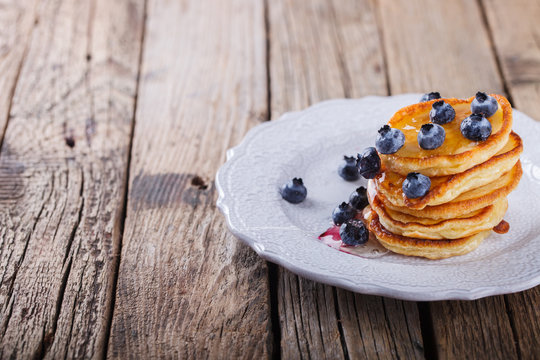 Pancake folded stack of with liquid honey and fresh blueberries on wooden background.Copy space.selective focus.