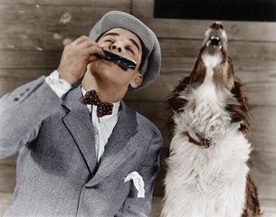 Man playing harmonica with howling dog  