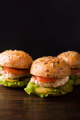 Three burgers, potatoes rustic, tomato on a dark wooden table