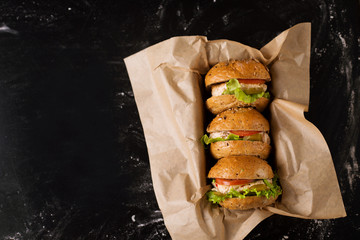 Three burgers on a dark background, in the craft, view from above