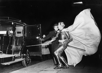Knight with billowing cape approaching car 