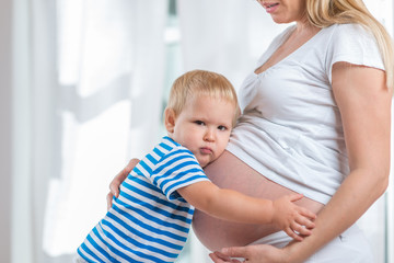 Kid boy hugging pregnant mother's belly