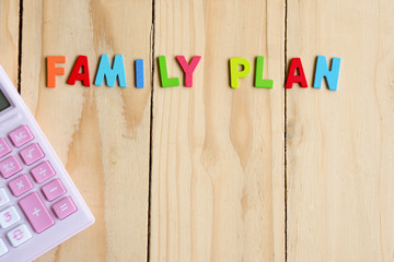Family planning text with pink calculator on wood table backgound