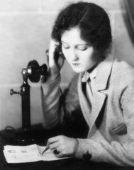 Closeup of a woman talking on the telephone and drawing on a sheet of paper 