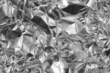 Silver foil background with shiny crumpled uneven surface for te